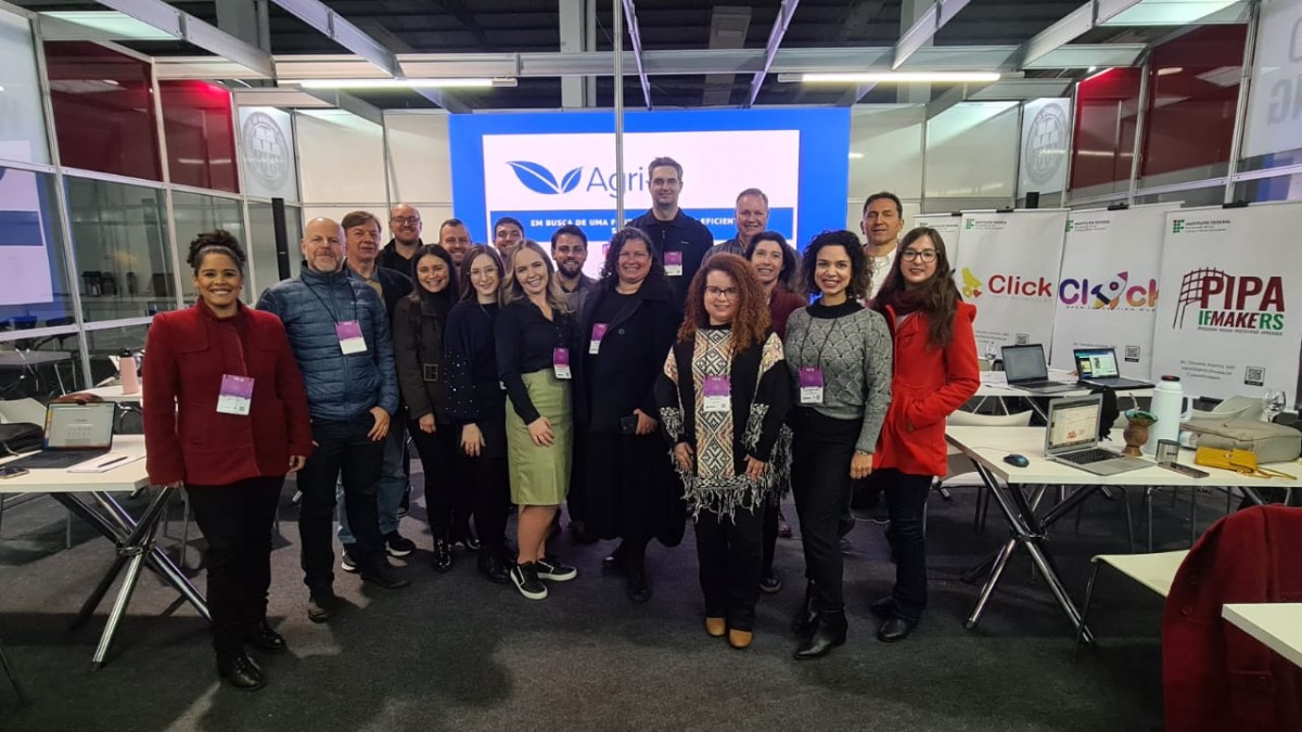 Pessoas reunidas em frente ao painel do evento 